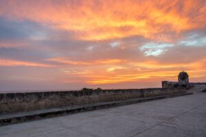 View of the historic defensive wall of Cartagena, Colombia during a fiery orange sunset